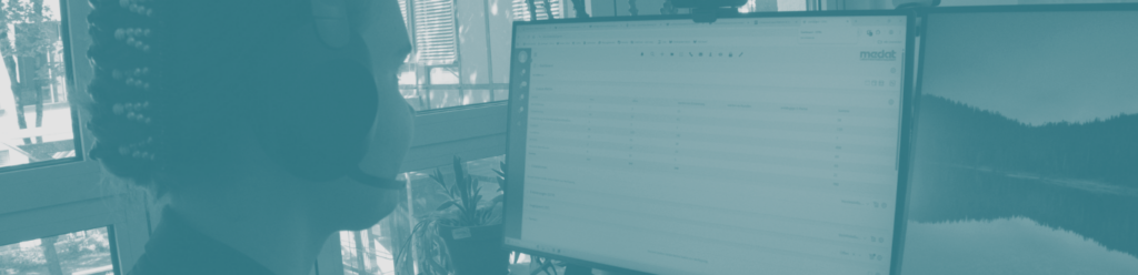Medat Support-Mitarbeiter mit Headset bei der Arbeit am Bildschirm mit der LIS-Software.